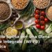 Lista della spesa per dieta vegetale integrale economica: cereali, legumi, verdure e frutta su un tavolo di legno chiaro